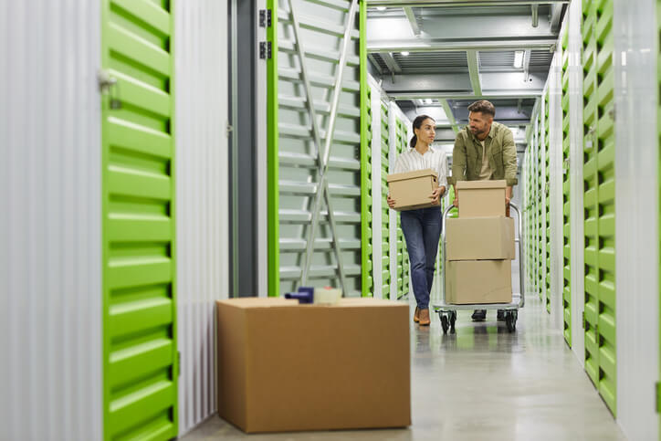 Couple moving boxes into an indoor storage unit