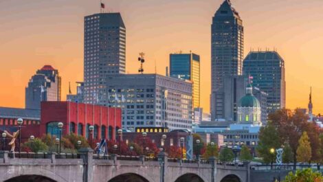 skyscrapers and other buildings in downtown Indianapolis with their lights on during a sunset