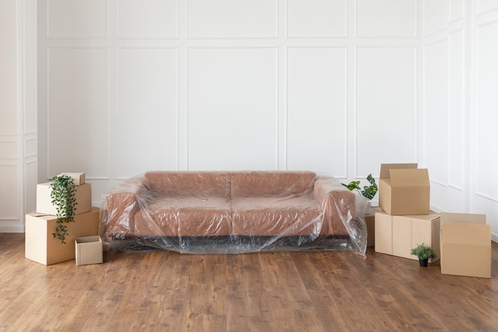 A couch covered alongside storage boxes 