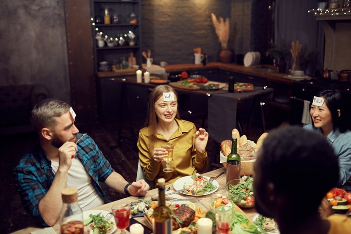 A group of friends playing a game around a table with food.