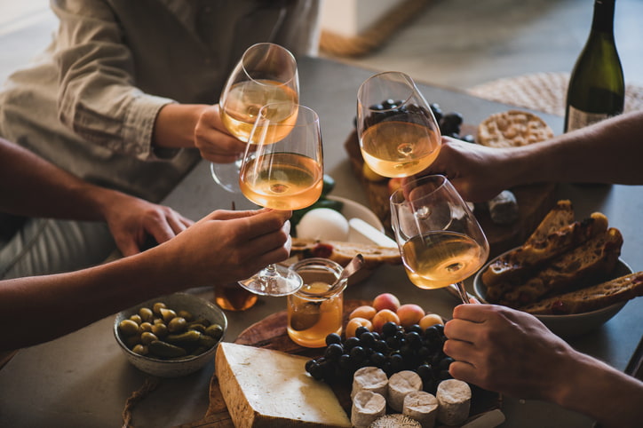 A group of friends cheering over wine and appetizers.