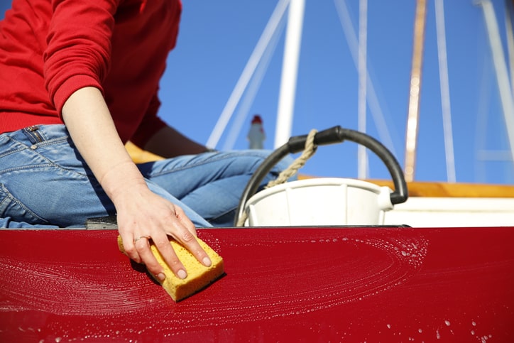 Person scrubbing exterior of a boat