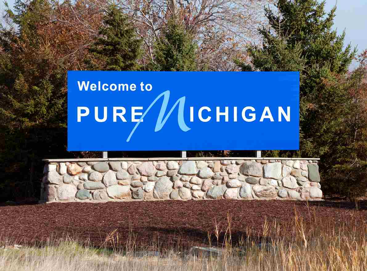 A bright blue sign outdoors reads Welcome to Pure Michigan