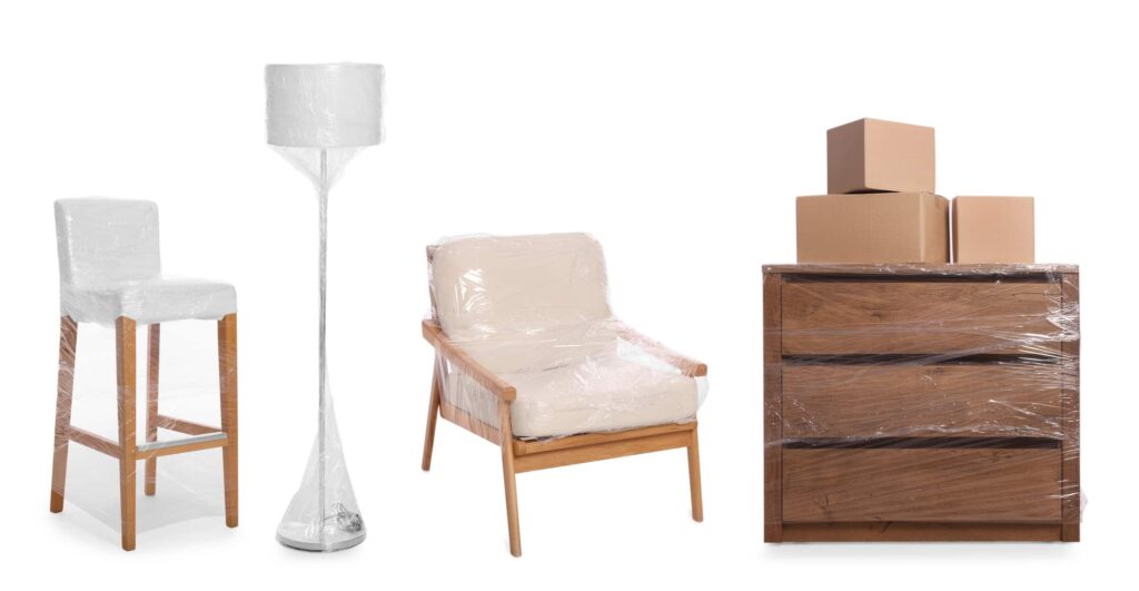 Chairs, a lamp, and a wooden dresser tightly wrapped in plastic.