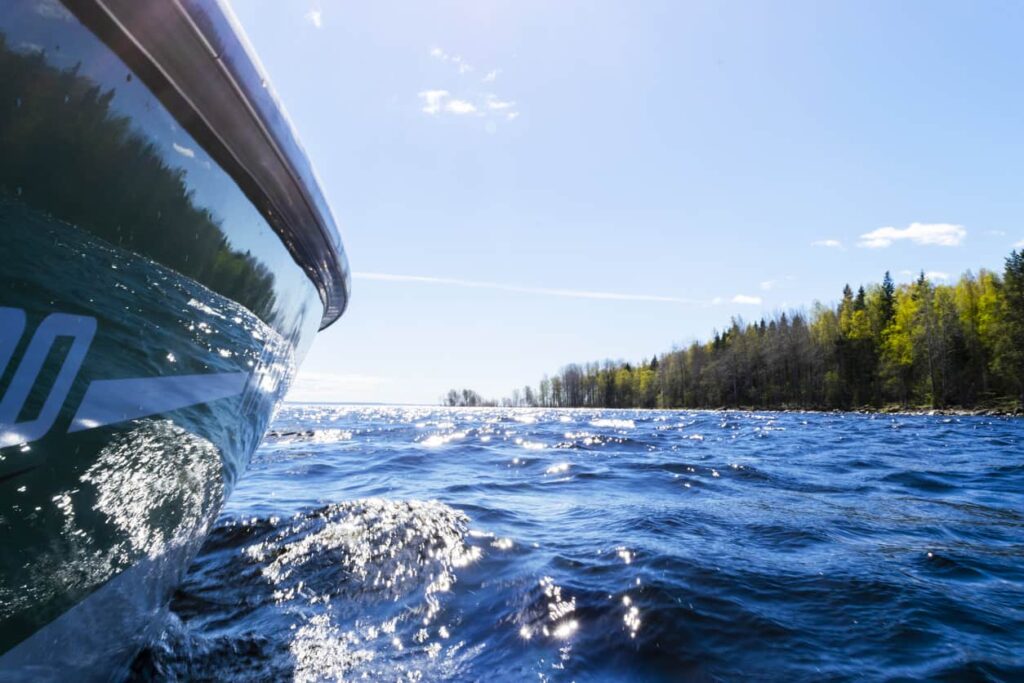 Side of a boat traveling on a lake.