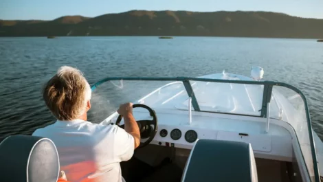 Man driving a boat on a lake.