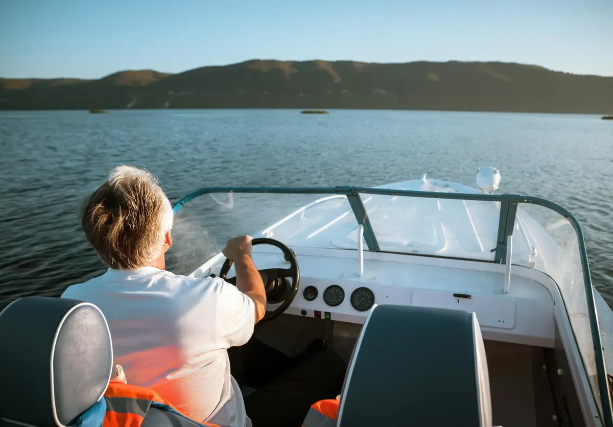 Man driving a boat on a lake.