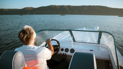Man driving a boat on a lake.
