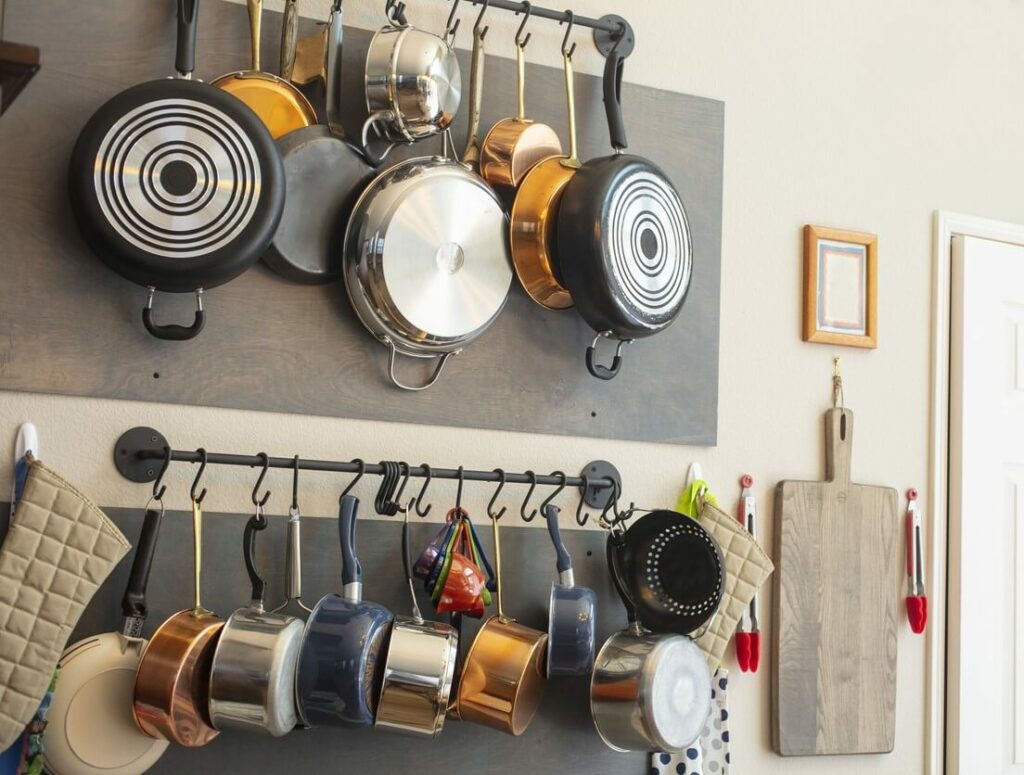 Pots and pans in different sizes and colors hang from wall-mounted racks.