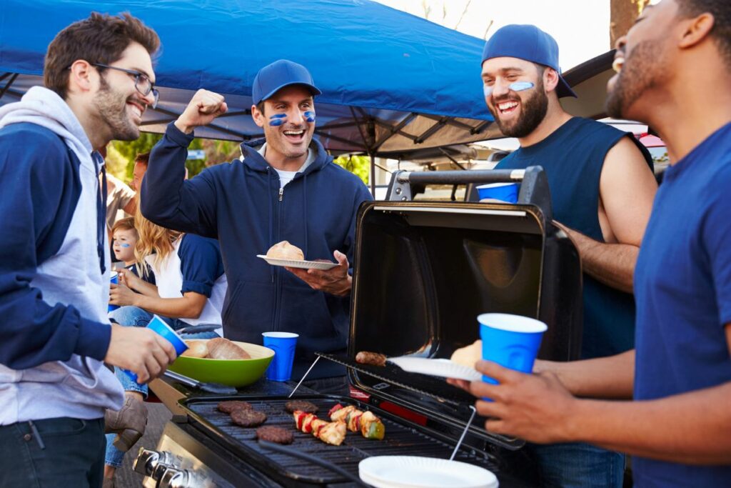 A group of friends tailgate outside of the stadium with drinks and food.