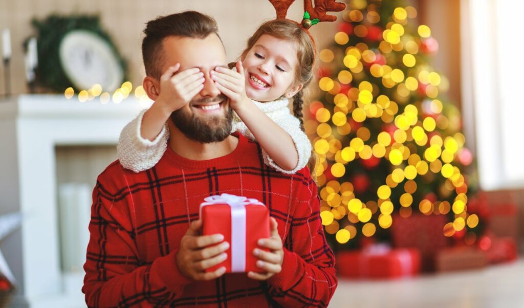 Child giving her father a Christmas gift.