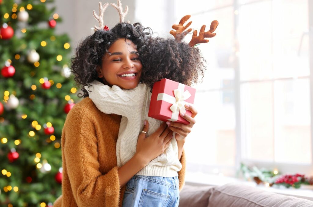 Mother with Christmas gift hugging daughter.